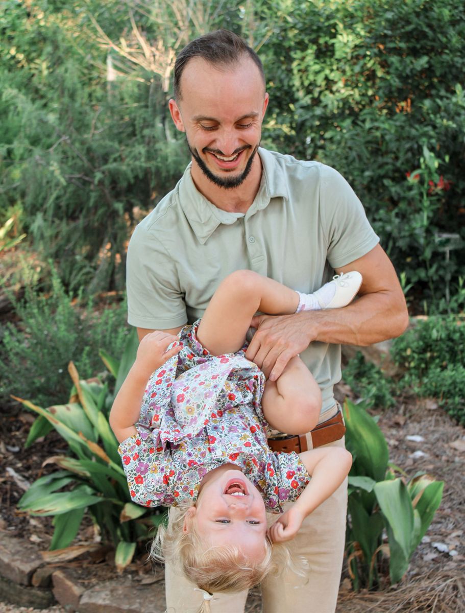 Dad playfully holding his giggling toddler upside down