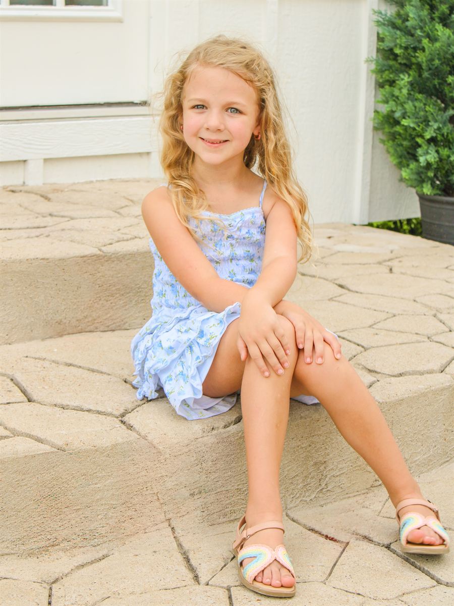 Young girl in a blue dress sitting on stone steps